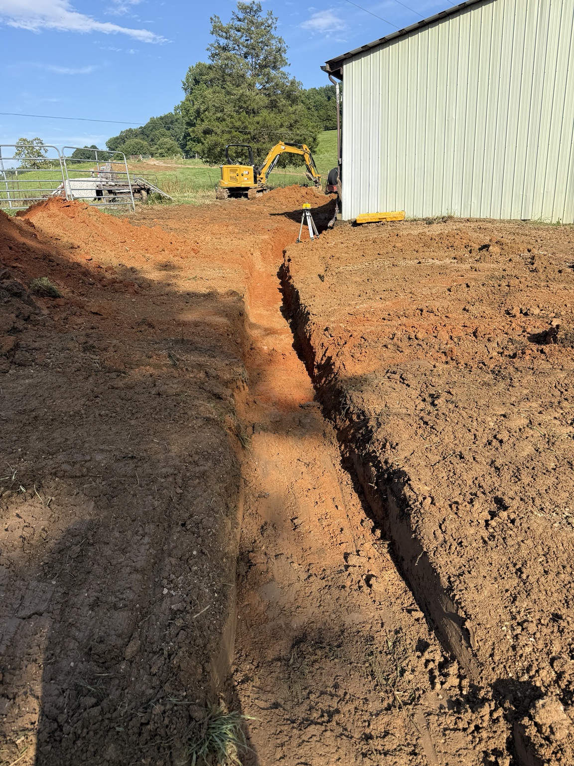 Excavated trench beside a metal building