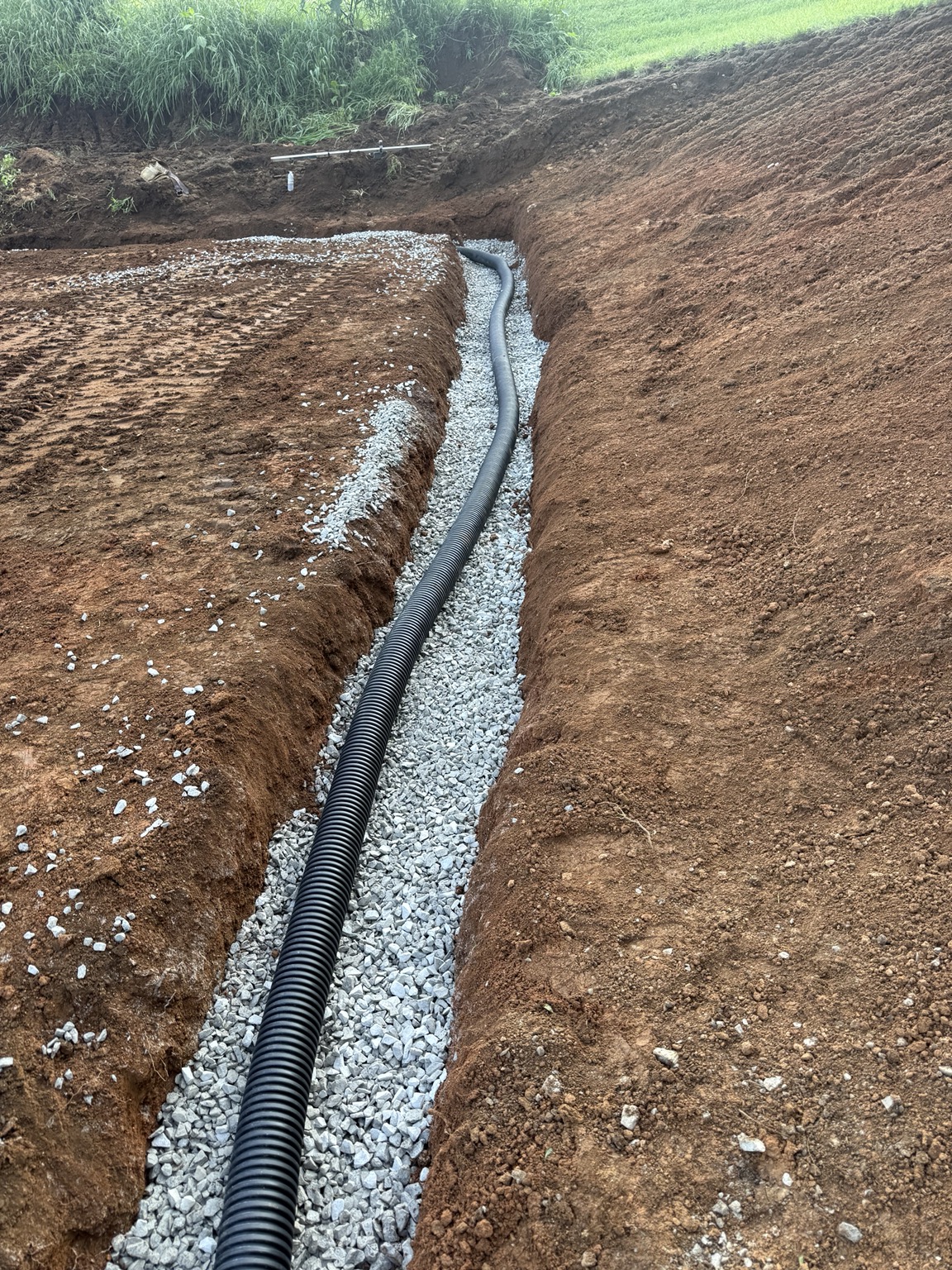 French drain style drainage pipe installed in stone trench